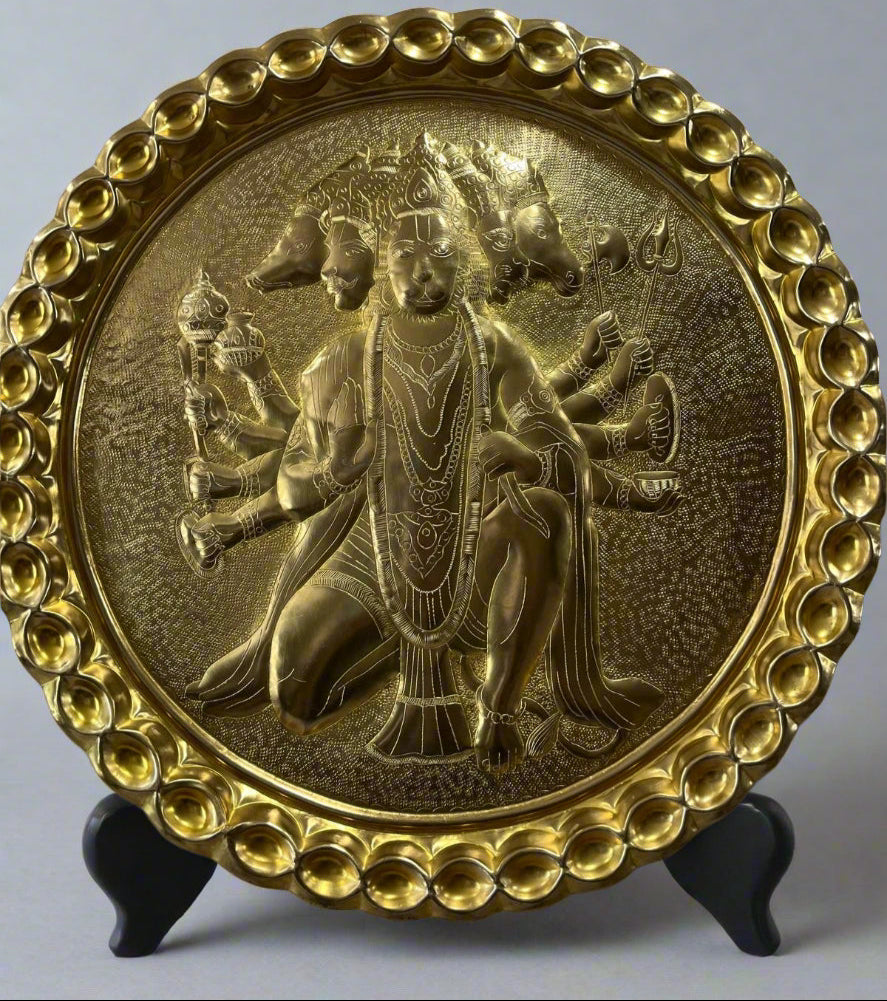 Decorative plate with a bronze embossed design of a seated figure on a gray background