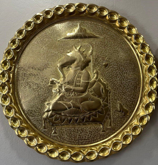 Decorative Brass plate with Lord Ganesha carving and intricate border on a gray background